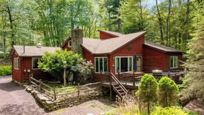 A cabin with a stone foundation, wooden deck, and a chimney. - Mins to Skiing! Hot Tub-Fire Pit-Hammock-BBQ-Games (Lake Harmony)