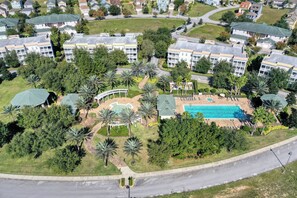 Vista aérea de una zona residencial con varios edificios de apartamentos, una piscina y vegetación circundante.