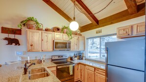 A kitchen with granite countertops, wooden cabinets, a stainless steel refrigerator, and a hanging light fixture. - 1 Mi to Stagecoach Lift! Homey Tahoe Townhome (Stateline)