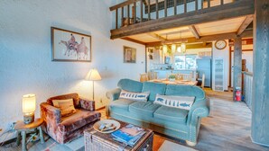 A cozy living room with a blue sofa, a brown armchair, and a wicker coffee table. A lamp and a framed picture adorn the wall. - 1 Mi to Stagecoach Lift! Homey Tahoe Townhome (Stateline)