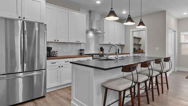 A modern kitchen with white cabinets, stainless steel appliances, and a central island with bar stools.