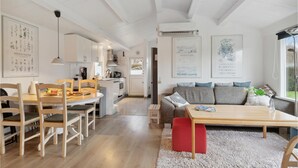 A modern kitchen with white cabinets, a dining area with wooden chairs, a sofa with patterned cushions, and a coffee table. - Nice home in Slagelse with WiFi (Slagelse)