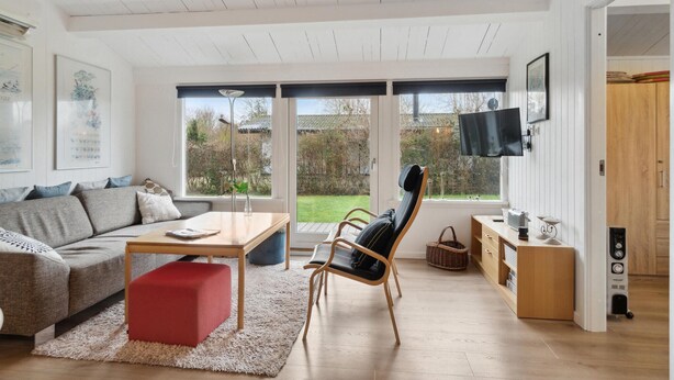 A modern living room with a sofa, a red ottoman, a wooden coffee table, a black chair, and a TV mounted on the wall. - Nice home in Slagelse with WiFi (Slagelse)