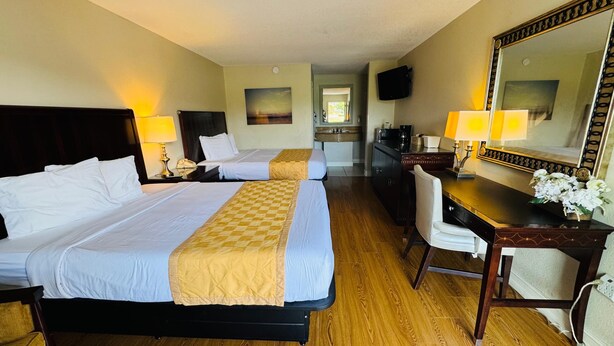 A hotel room with two beds, a desk, a chair, a mirror, and a small kitchenette. - Hotel MonteCarlo (Kissimmee)