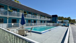 A motel with a swimming pool, outdoor seating, and a two-story building. - Hotel MonteCarlo (Kissimmee)