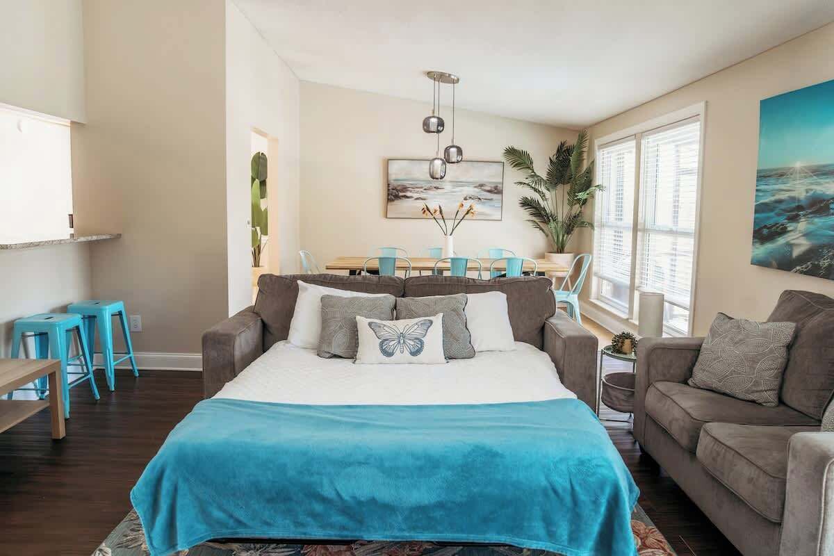 A bedroom with a bed, a sofa, a dining table, and chairs.