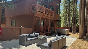 A two-story wooden cabin with a balcony, outdoor seating area, and a barbecue grill. - Luxury House, Hot Tub, Pet Friendly, Pool Table, EV Charger
 (South Lake Tahoe)