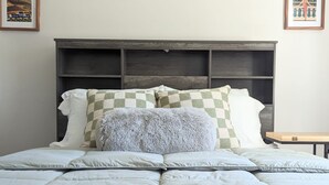 A neatly made bed with a checkered pillow, a knitted throw, and a wooden headboard. - Downtown Villa-Fully equipped! Short drive Beaches, Short Walk to Payne Park.  (Sarasota)