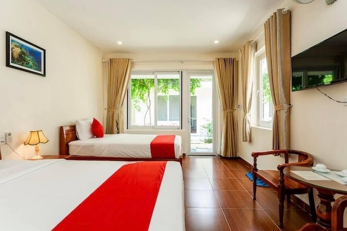 Ein Hotelzimmer mit zwei Betten, einem Fernseher, einem Schreibtisch und Blick ins Freie.