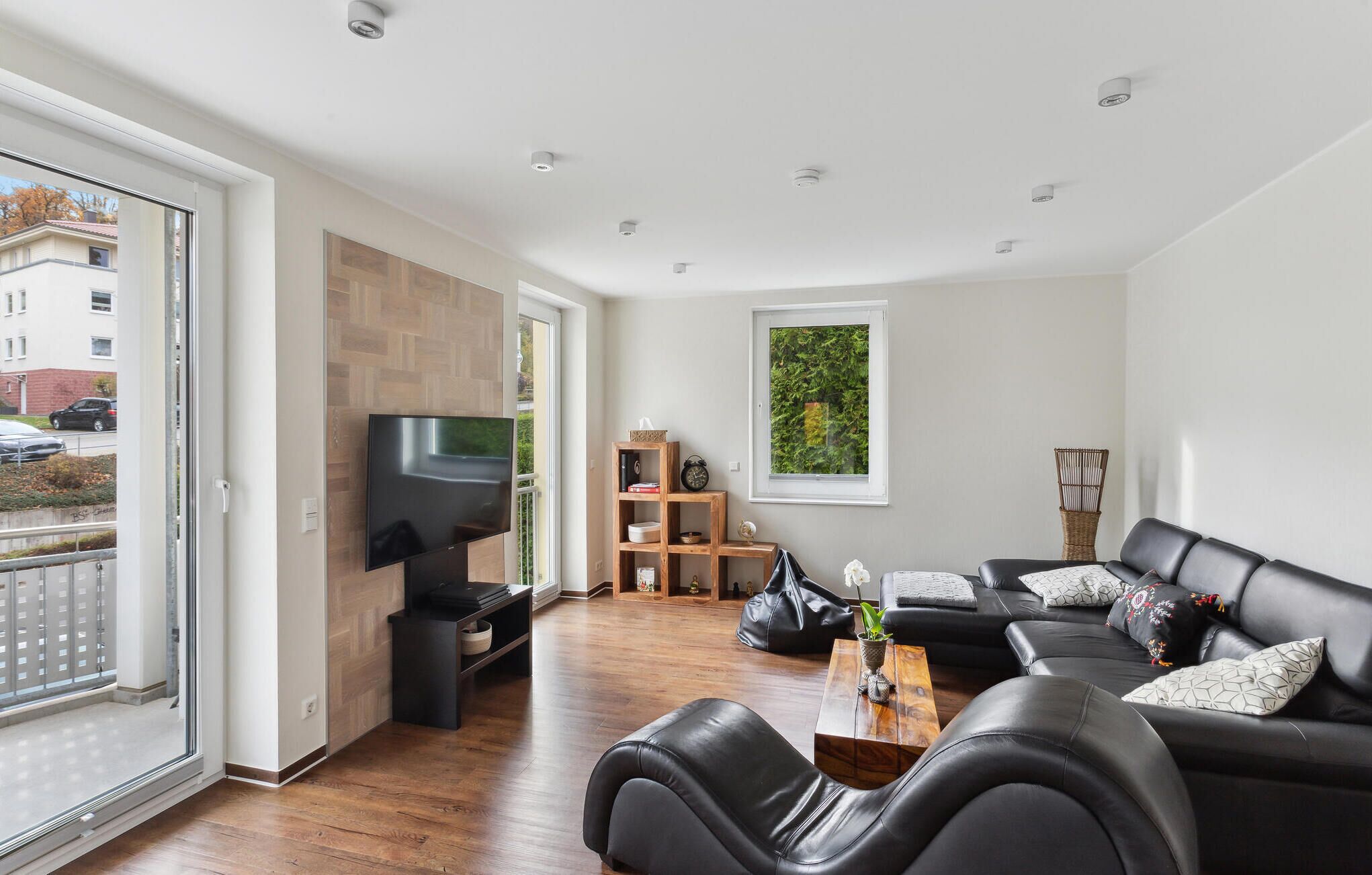 A modern living room with a flat-screen TV, leather sofa, and a wooden coffee table.