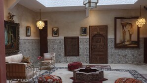 A spacious interior with a high ceiling, patterned walls, and a central seating area with ottomans and a coffee table. - Riad la fayette bed & breakfast  (Marrakech)