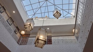 A high-ceilinged atrium with geometric ceiling design, hanging lantern-style lights, and intricate white wall patterns. - Riad la fayette bed & breakfast  (Marrakech)