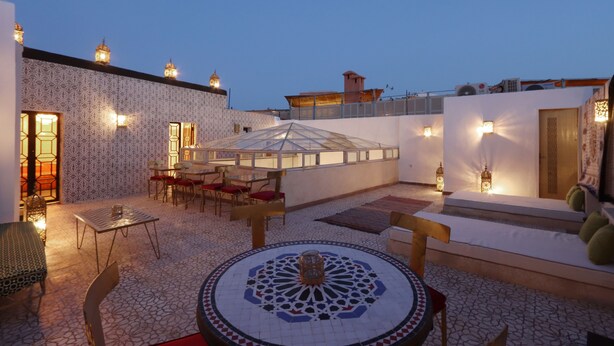 A rooftop terrace with a patterned floor, a central decorative table, and seating areas. - Riad la fayette bed & breakfast  (Marrakech)