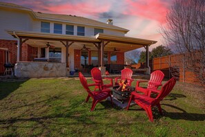 Un patio techado con sillas Adirondack rojas y una chimenea.