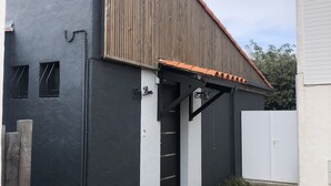 A building with a black facade, a wooden roof, and a white door marked with the number 9. - BIG BEN - à 750m de la Plage (Les Sables-d´Olonne)