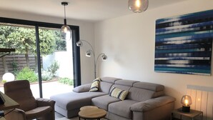 A modern living room with a sectional sofa, a round coffee table, and a floor lamp. - BIG BEN - à 750m de la Plage (Les Sables-d´Olonne)