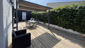 A covered outdoor patio with a table and chairs, a pergola, and a hedge. - BIG BEN - à 750m de la Plage (Les Sables-d´Olonne)
