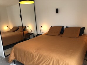 A hotel room with two beds, each with a matching headboard, and a large mirror on the wall.