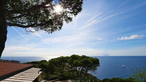 Una propiedad costera con terraza, vista al mar y un velero.