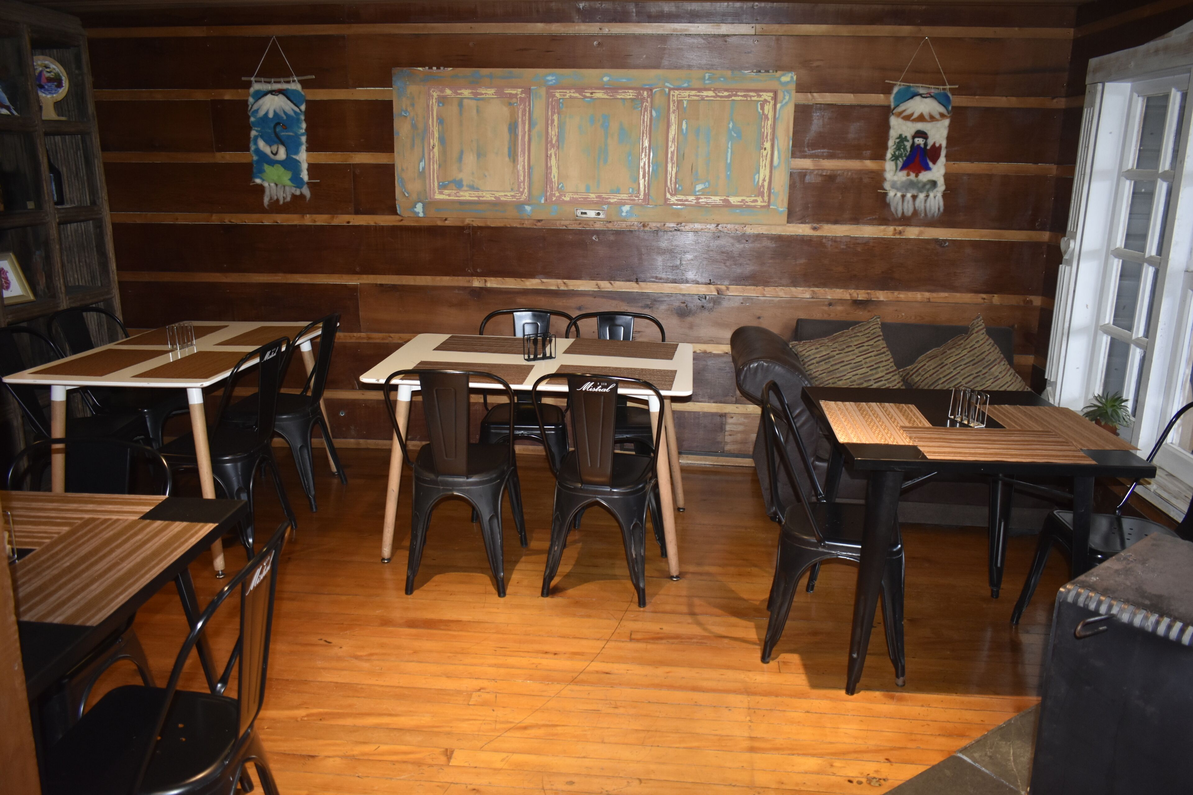 Un restaurante acogedor con paredes de madera, varias mesas y sillas, y adornos decorativos en las paredes.