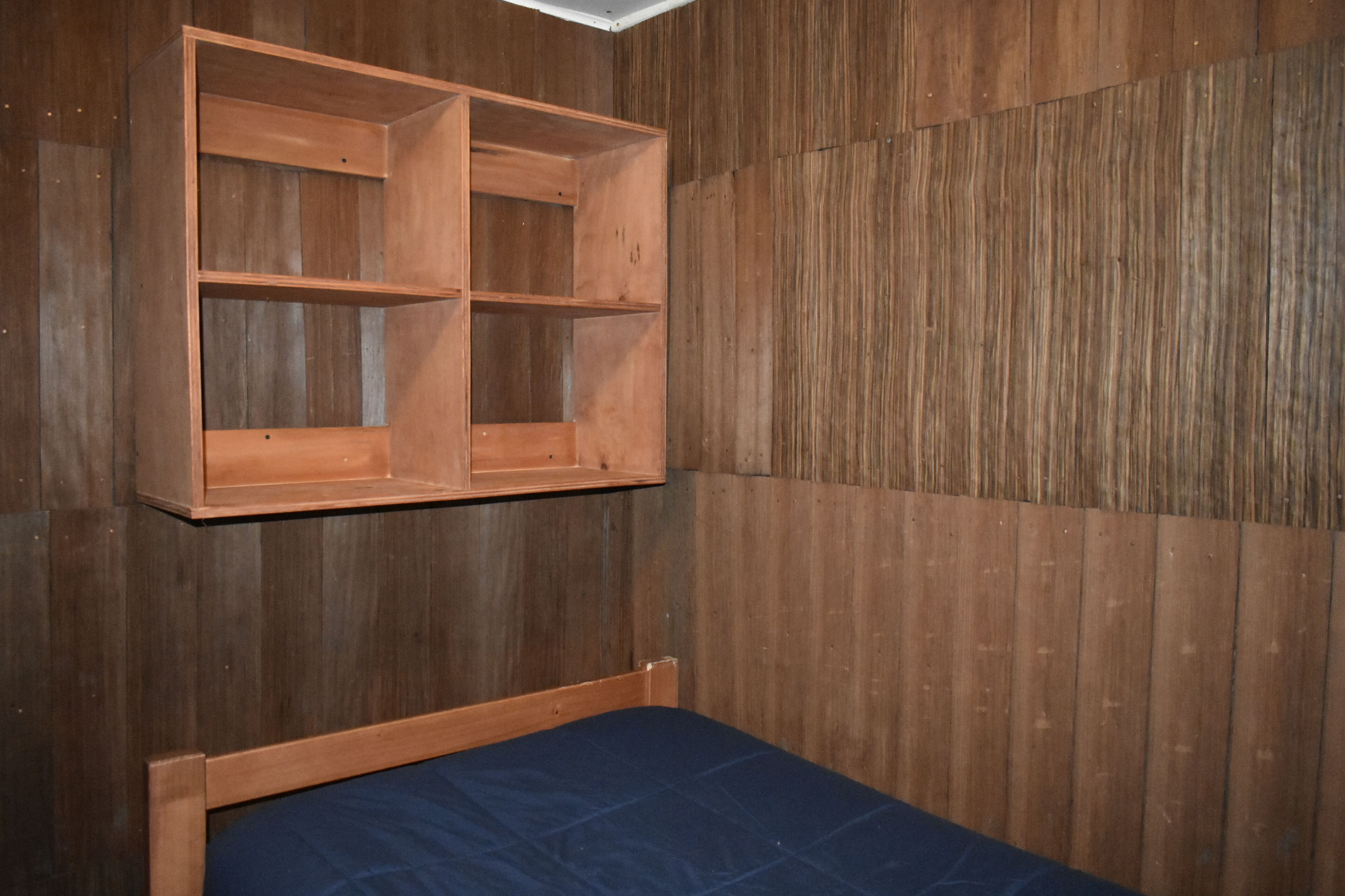 Una habitación con una cama litera de madera y una estantería empotrada.