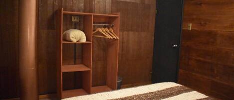 Un dormitorio con un armario de madera, una cama con manta a rayas y una puerta oscura.