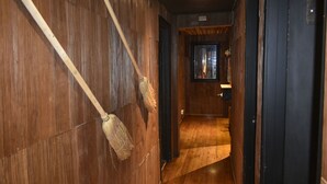 Un estrecho pasillo con paredes y suelo de madera que conduce a una habitación con una ventana y una puerta.
