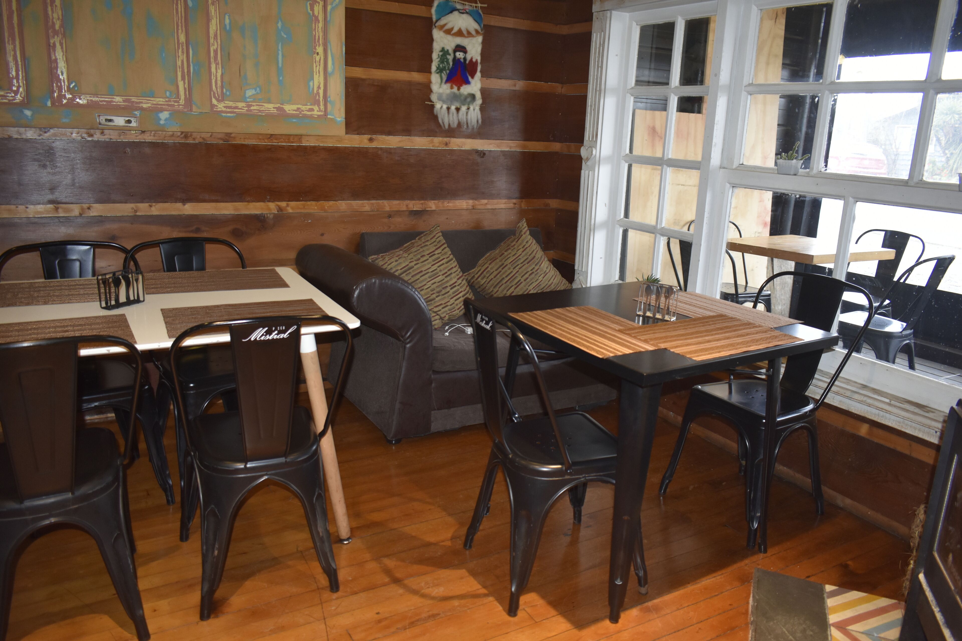 Un comedor acogedor con mesas y sillas de madera, un sofá y un ventanal con vistas.