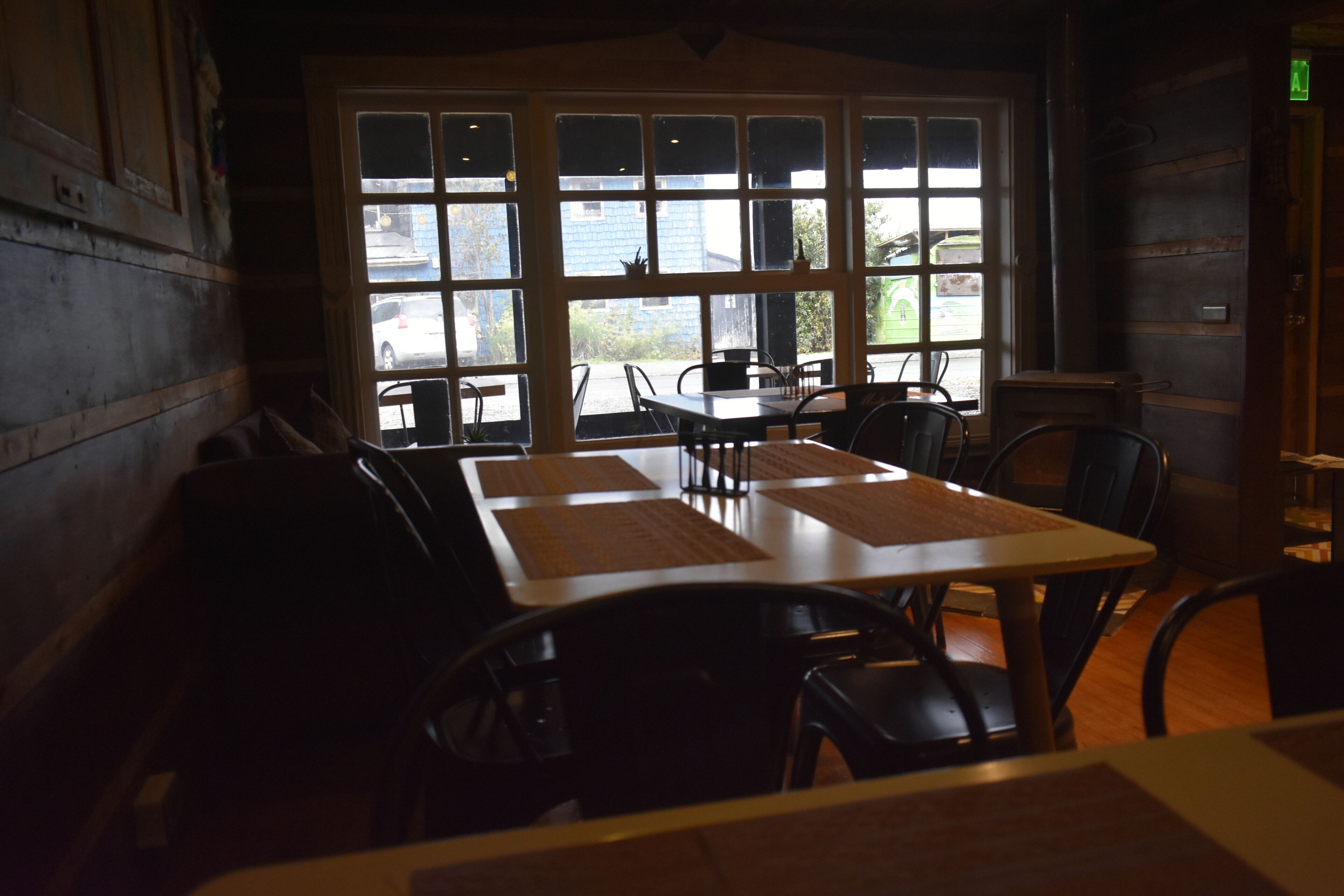 A restaurant with a large window, wooden walls, and a table with chairs.