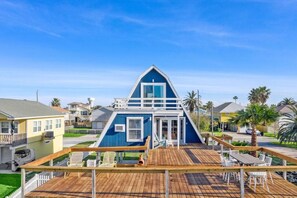 A blue house with a wooden deck and outdoor seating.