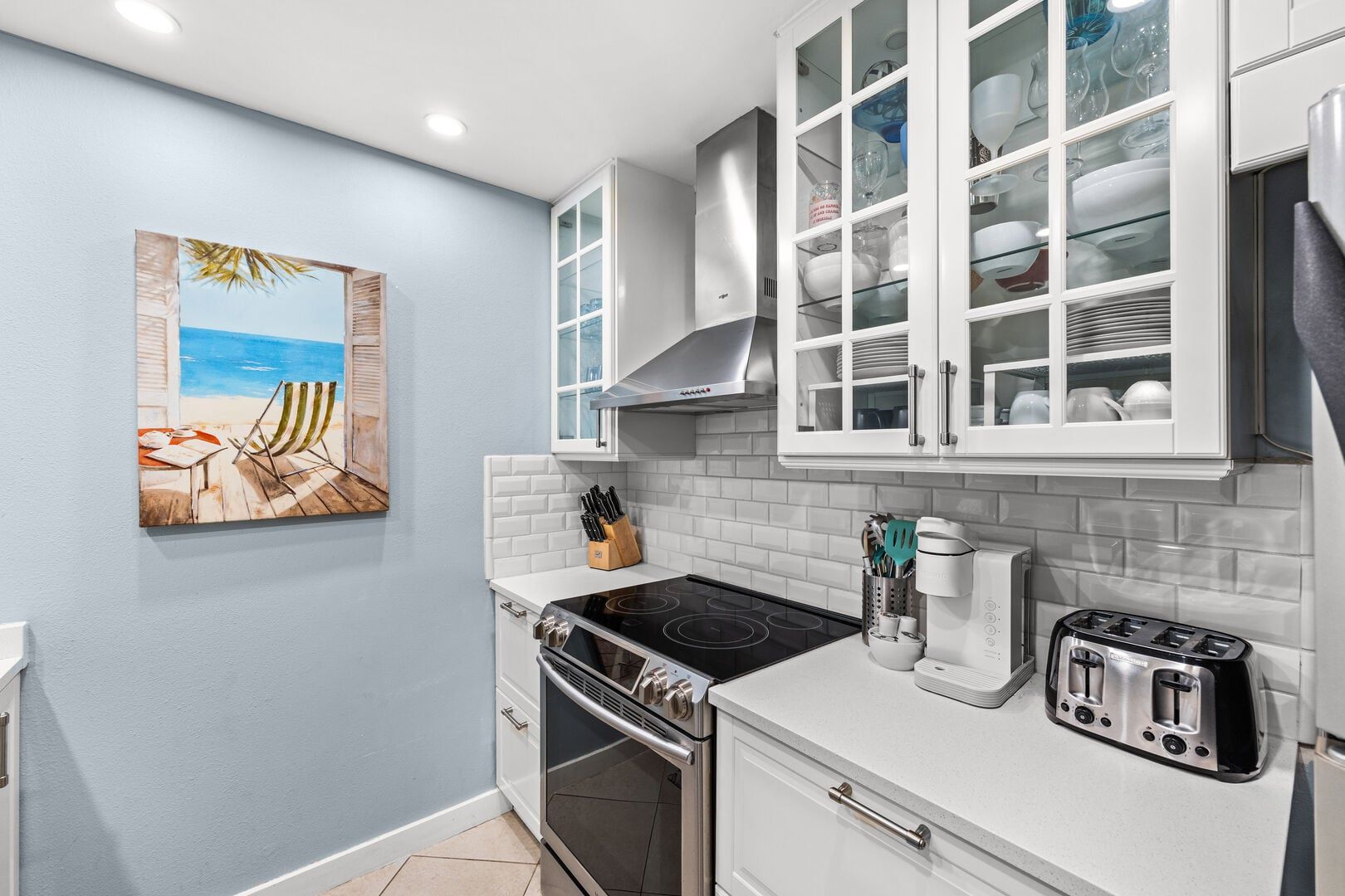 A kitchen with white cabinets, a stove, a toaster, and a coffee maker.