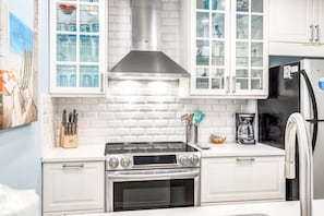 Una cocina con armarios blancos, una estufa de acero inoxidable y un refrigerador negro.