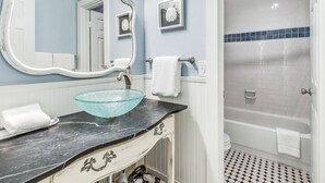 A bathroom with a glass bowl sink, a white vanity, a large mirror, a towel rack, a framed picture, and a shower with a tiled floor. - Cassine- 3 Min to Beach, 2 BR, Pool, Bikes, Tennis & Beach (Santa Rosa Beach)