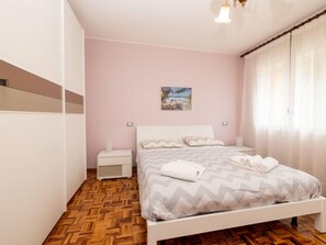 Un dormitorio con cama, mesitas de noche, un cuadro y suelo de parquet de madera.
