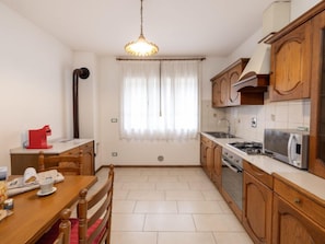 Una cocina compacta con armarios de madera, estufa a gas, microondas y un comedor con mesa y sillas.