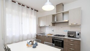 Une cuisine moderne avec une table blanche, des chaises grises et une cuisinière à gaz.