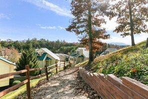 A pathway leading to a row of cabins with a wooden fence on one side and a grassy hill on the other.