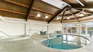 An indoor swimming pool with a wooden ceiling and stone flooring.