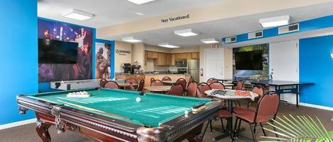 Une table de billard, un espace repas avec des chaises et une table.