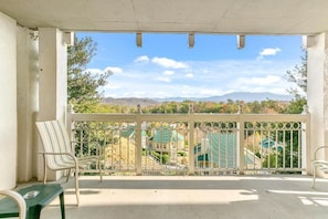 A balcony with a view of buildings and mountains. - Pigeon Forge | Family Smoky Getaway | Pool + Hot Tub | 2BR (Pigeon Forge)