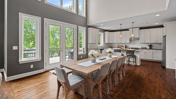 A spacious kitchen with a large island, white cabinetry, and a view to a balcony. - Ruby Arrival by SoCharm | Luxury on Lake Norman (Mooresville)