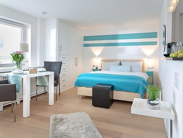 A modern bedroom with a bed, bedside table, and a small desk area.
