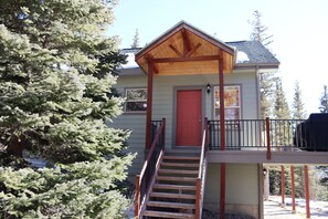 A two-story house with a red door, wooden balcony, and a staircase leading to the upper floor. - Riverfront Hot Tub & Starlink - South Platte Frontage, 15mi to Breck (Alma)