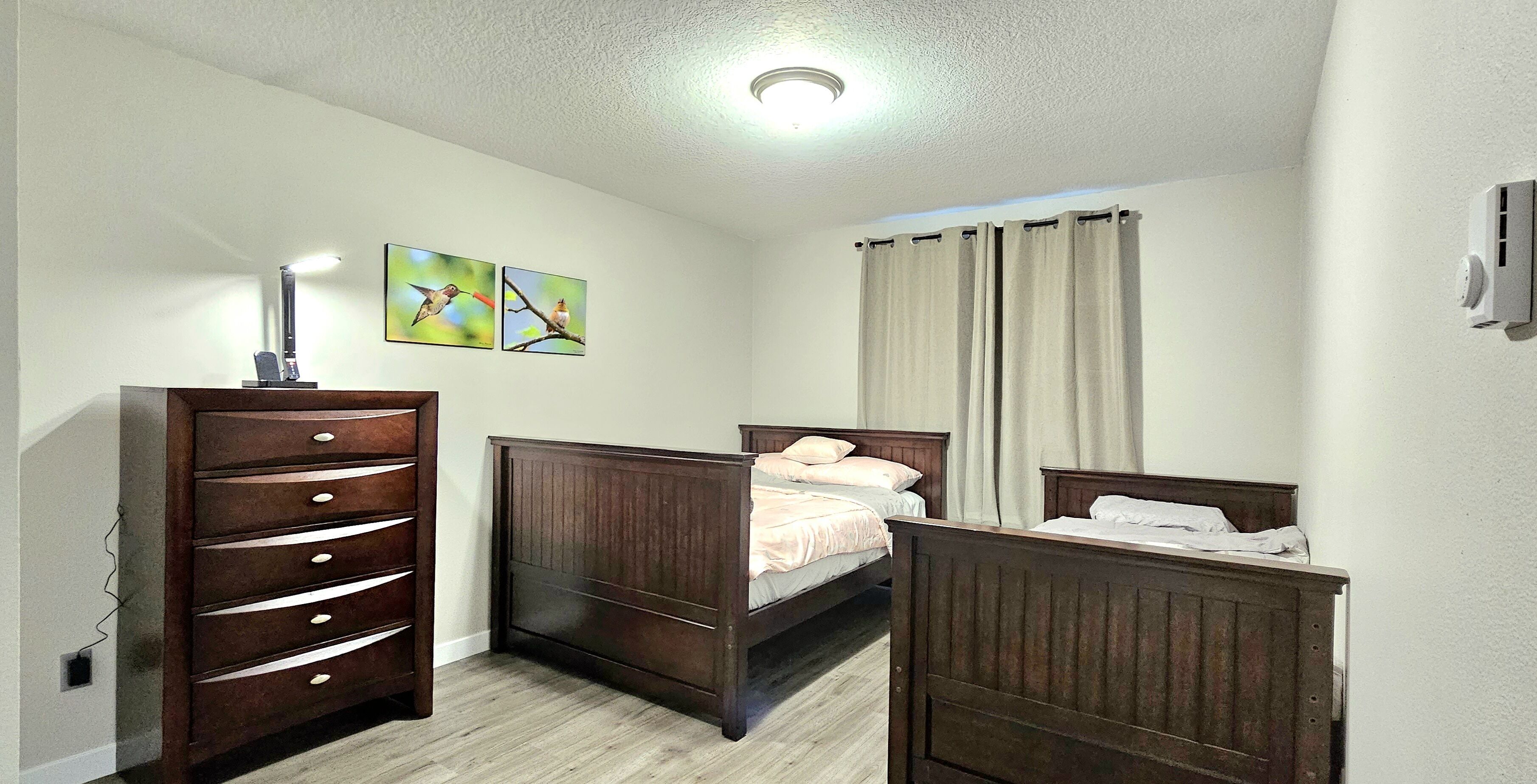 Ein Schlafzimmer mit zwei hölzernen Betten, einem Schminktisch und zwei an der Wand hängenden Bildern.