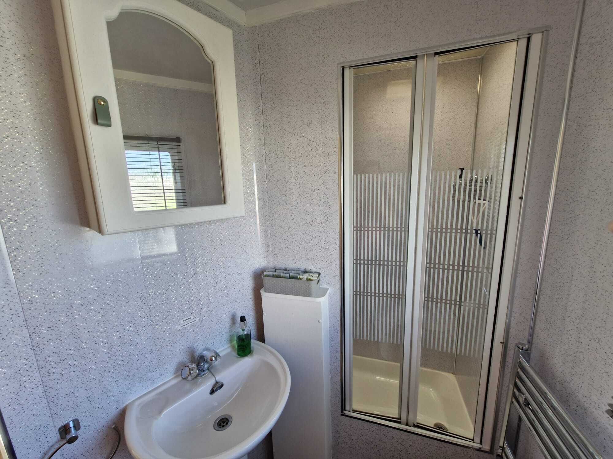 A bathroom with a white sink, a mirror, and a glass-enclosed shower.