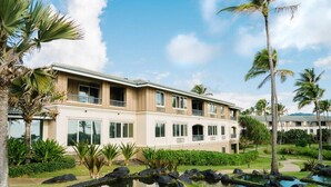 Ein mehrstöckiges Hotel mit Poolbereich, Palmen und einem gepflegten Garten.