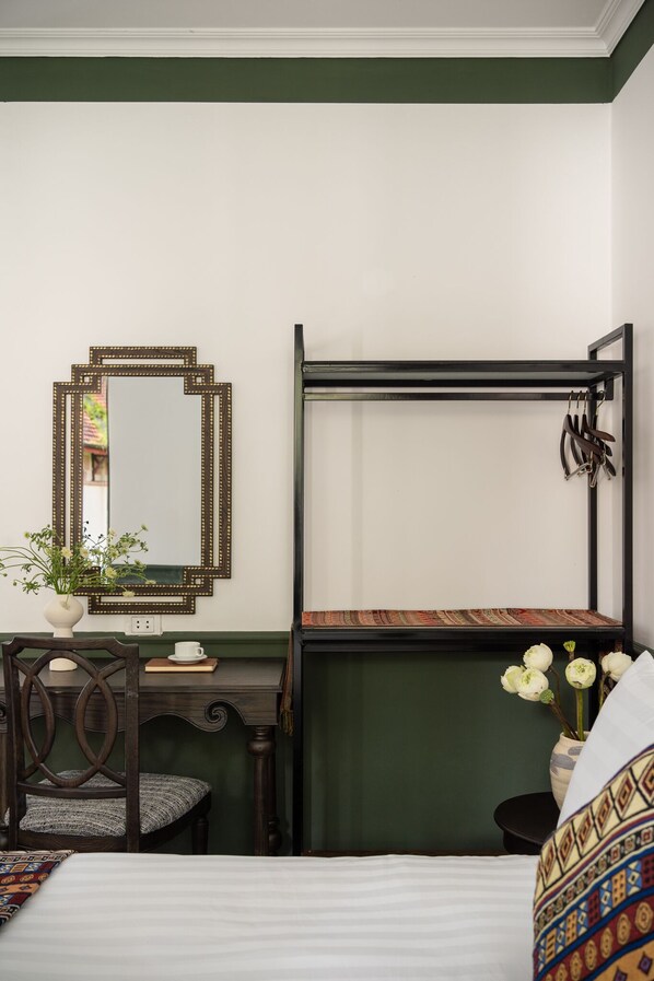 A bedroom with a bed, a desk with a chair, a mirror, and a shelf with decorative items. - The Gate Boutique Hotel Sapa (Sa Pa)