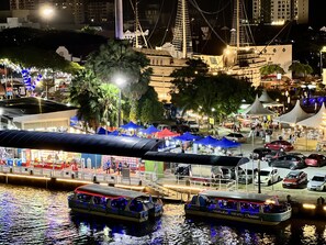 Una zona costera nocturna con barcos, carpas y un puente.