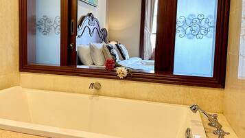 A bathroom with a large bathtub, a mirror above it, and decorative wall patterns.