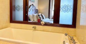 Un baño con una bañera grande, un espejo encima y diseños decorativos en la pared.